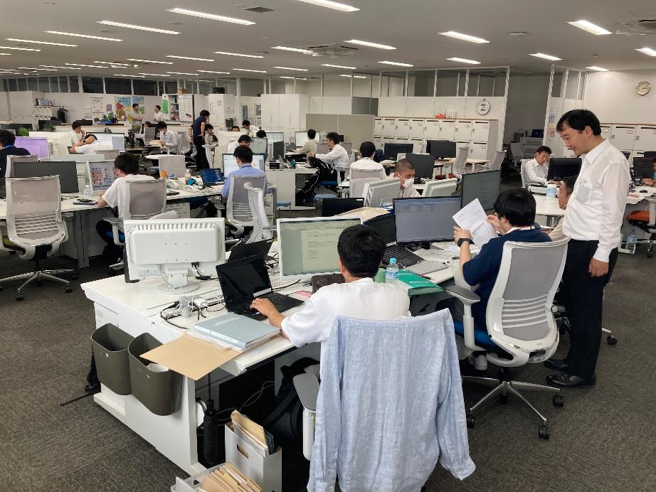 JR西日本のIT系統のオフィス風景。多くの社員がPCに向かい、WESTERやモバイルICOCAなどのデジタル戦略(IT戦略)を支えるシステム開発や企画に取り組むチームワークの様子。