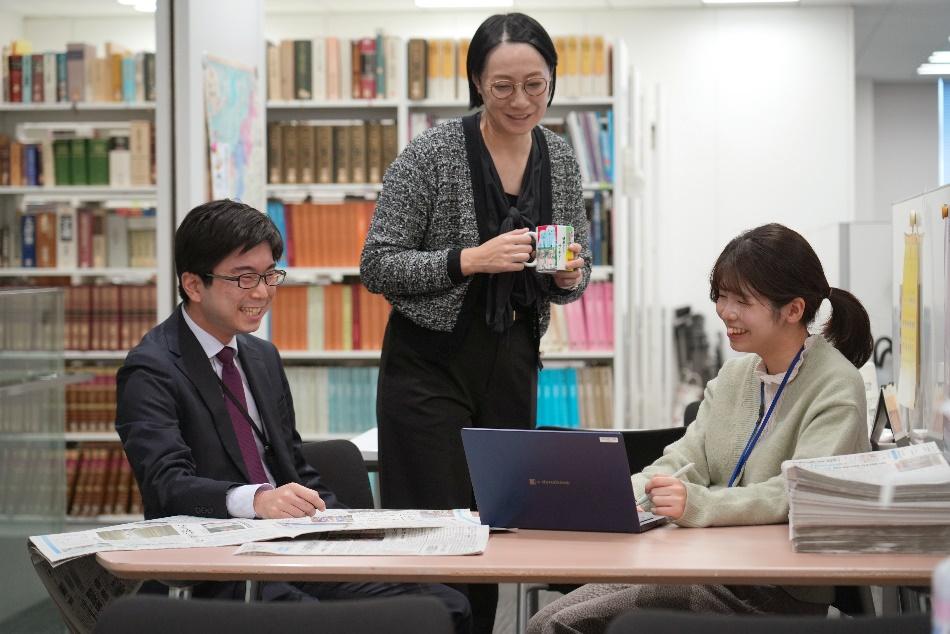 新潟日報社のオフィスで、年次や部署を越えて和やかに議論する社員たち。自由な言論の風土を象徴する打ち合わせ風景。