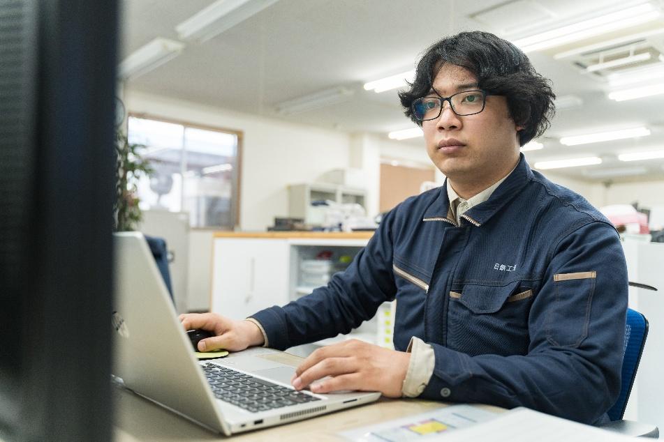 日鉄工材株式会社のオフィスにて、PCで設計や製品開発の業務を行う技術職の社員。