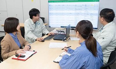 キヤノントッキの社内会議の様子。4名の社員がスクリーンに映った情報を見ながらミーティングしている。